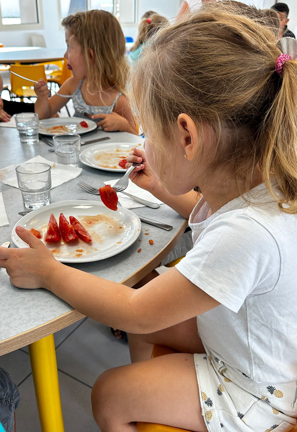 Repas au restaurant scolaire Les Marronniers, petite fille mangeant des tomates